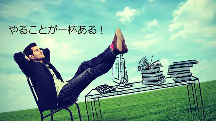 デスクの上に足を上げて休みながら、忙しいという男性