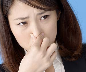 鼻をつまむ女性