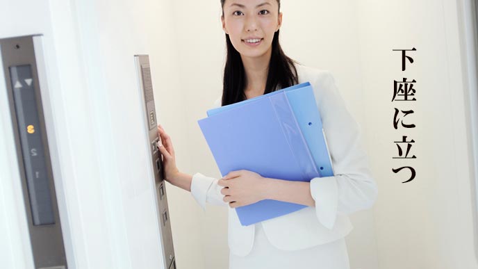 エレベーターの操作ボタンに近い場所に立つ女性