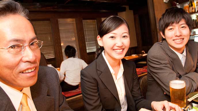 居酒屋で上司と一緒に並んで座る会社員