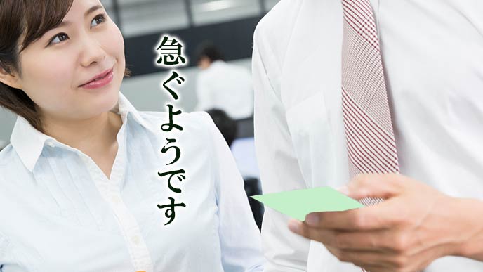 メモを男性社員に渡して一言添える女性社員