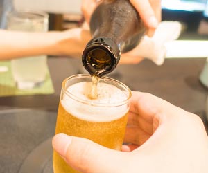 両手でお酒の瓶を持ってお酌する