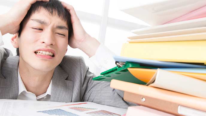 書類の山を見ながら頭を抱える社員