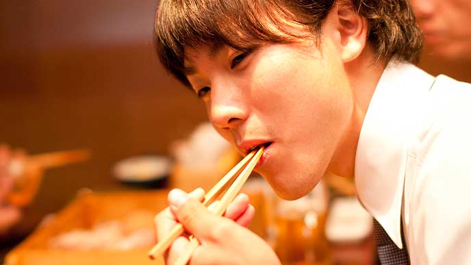 飲み会で食事を頬張る会社員