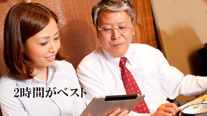 飲み会の席で上司にタブレットを見せる