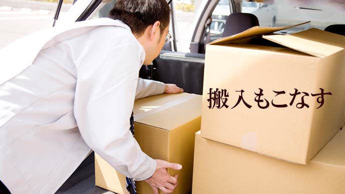 車で荷物を運ぶ営業マン