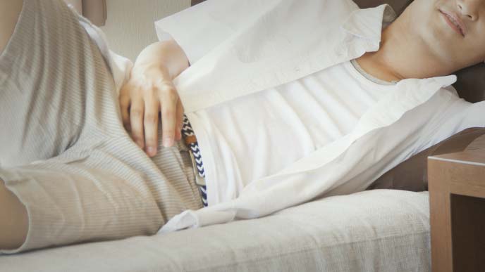 ソファで寝転がる半そで半ズボンの若い男性