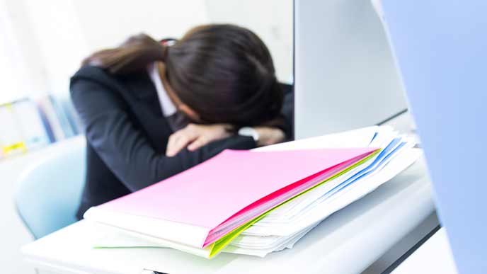 会社のデスクで腕枕をして寝る女性社員