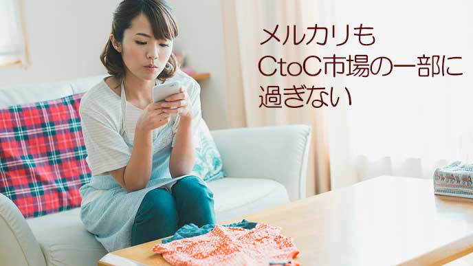 売りに出す子供服をスマホで撮影する女性