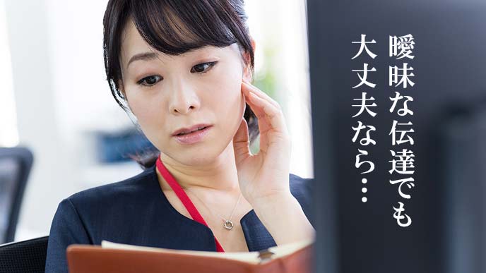 会社のPCの前でメール文を考える女性