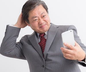 メールを見て苦笑いする年配社員