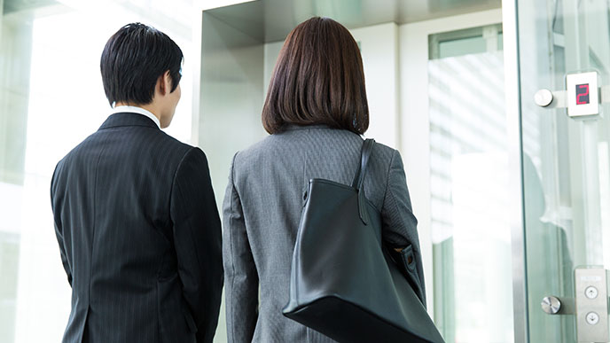 エレベーターが来るのに待つ社員