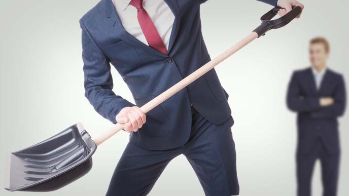 スコップを持って働くスーツ姿の男性