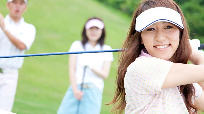 ゴルフをする女性と仲間