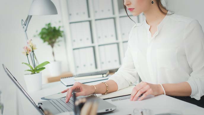書類をめくりながらキーボードを打つ女性事務員