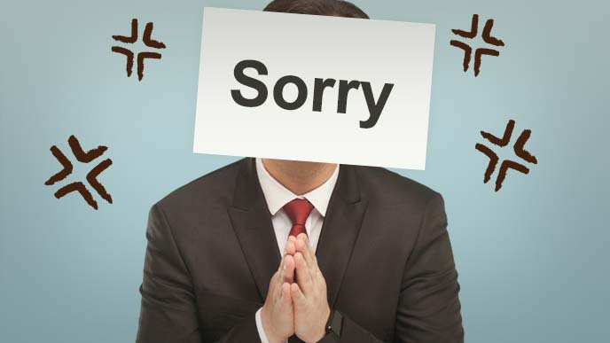 Sorryと書いた紙を顔に貼って手を合わせる男性