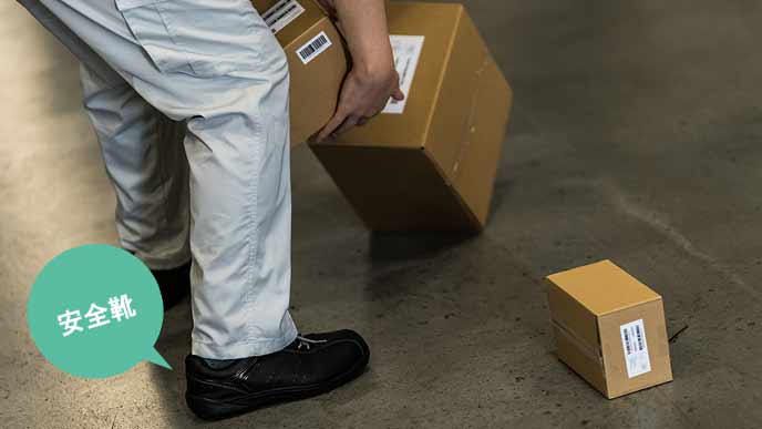 荷物を足元に落とす作業員