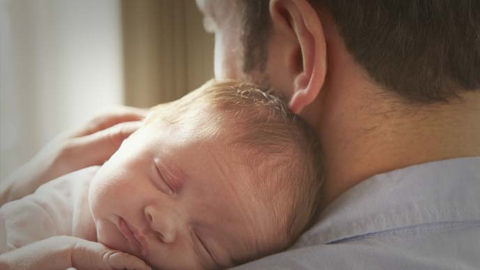 赤ちゃんを抱っこする男性の後ろ姿