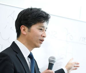 ワイトボードの前に立って話す男の人