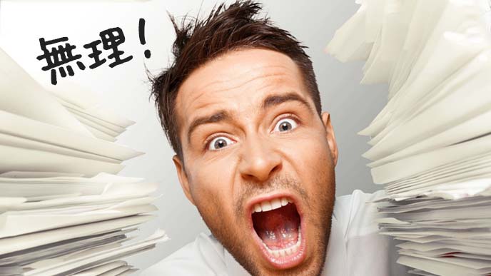 書類の山の中心で無理と叫ぶ男性