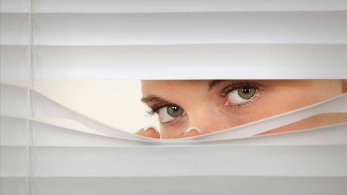 ブラインドから顔をのぞかせる女性