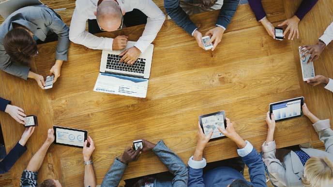 テーブルを囲んで黙々と端末を操作する社員たち