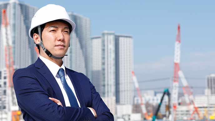 ゼネコンの社員がスーツ姿で工事現場に立つ